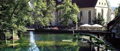 A church with a prominent tower and a calm water body in front.