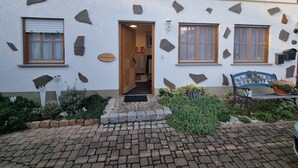 A building with a stone facade, a wooden door, and a bench with potted plants. - Studio Apartment "Kuckuck" with Wi-Fi (Ohlsbach)