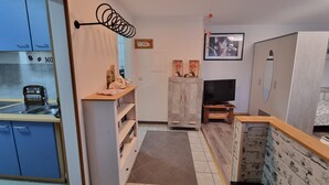 A compact hotel room with a kitchenette, a TV, a wardrobe, and a small seating area. - Studio Apartment "Kuckuck" with Wi-Fi (Ohlsbach)