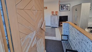 A modern interior with a wooden door, a grey cabinet, a television, and a framed picture on the wall. - Studio Apartment "Kuckuck" with Wi-Fi (Ohlsbach)