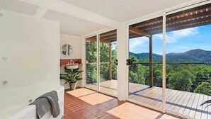 Ein Balkon mit Blick auf eine gebirgige Landschaft, einem Blumentopf und einem Handtuch auf einem Stuhl.