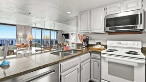 Une cuisine moderne avec des armoires blanches, un four à micro-ondes en acier inoxydable et une cuisinière blanche.