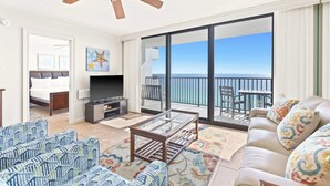 A spacious living room with a balcony overlooking the sea, a television, and a bed in the adjacent room. - One Seagrove Place 1507 (Santa Rosa Beach)