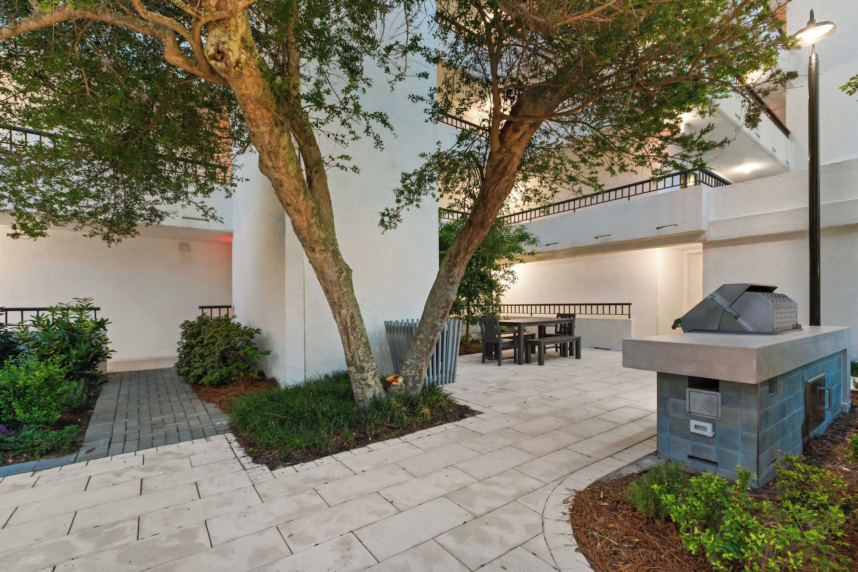A courtyard with a dining area, outdoor seating, and a barbecue grill.