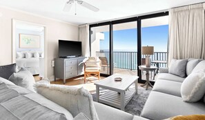 A modern hotel room with a balcony, a flat-screen TV, a sofa, and a dining table. - One Seagrove Place 1103 (Santa Rosa Beach)