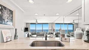 A modern kitchen with a marble countertop, a built-in dishwasher, and a large window overlooking the sea. - One Seagrove Place 0408 (Santa Rosa Beach)