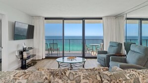 A modern hotel room with a large balcony, a flat-screen TV, a round coffee table, and a sofa. - One Seagrove Place 1706 (Santa Rosa Beach)