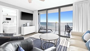 Ein modernes Hotelzimmer mit Balkon, Flachbildfernseher, Sofa und Essbereich.