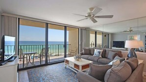 Une chambre d’hôtel avec un balcon, un canapé, une table basse et un téléviseur.