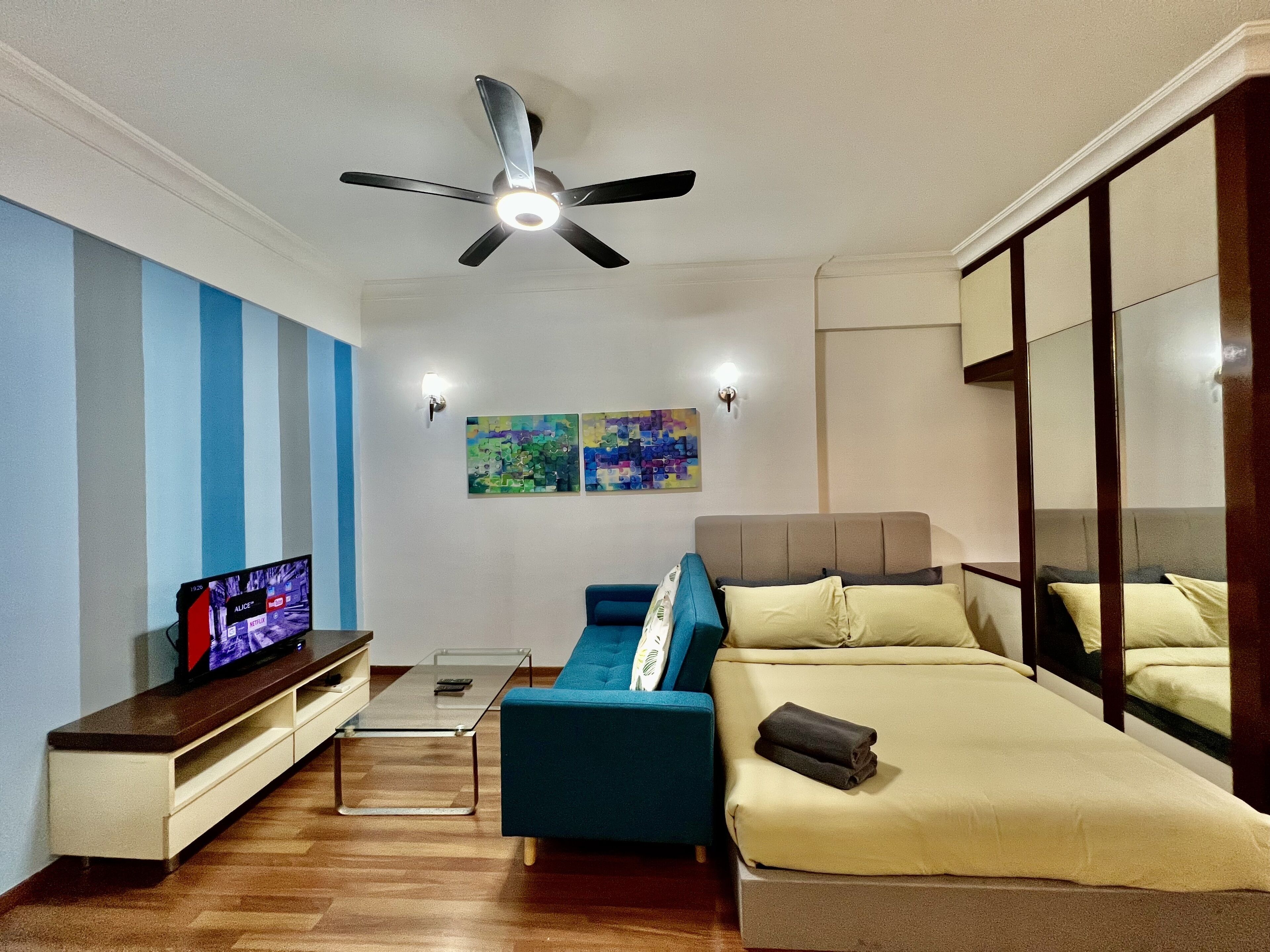 A modern living room with a sofa, a TV, and artwork on the wall.