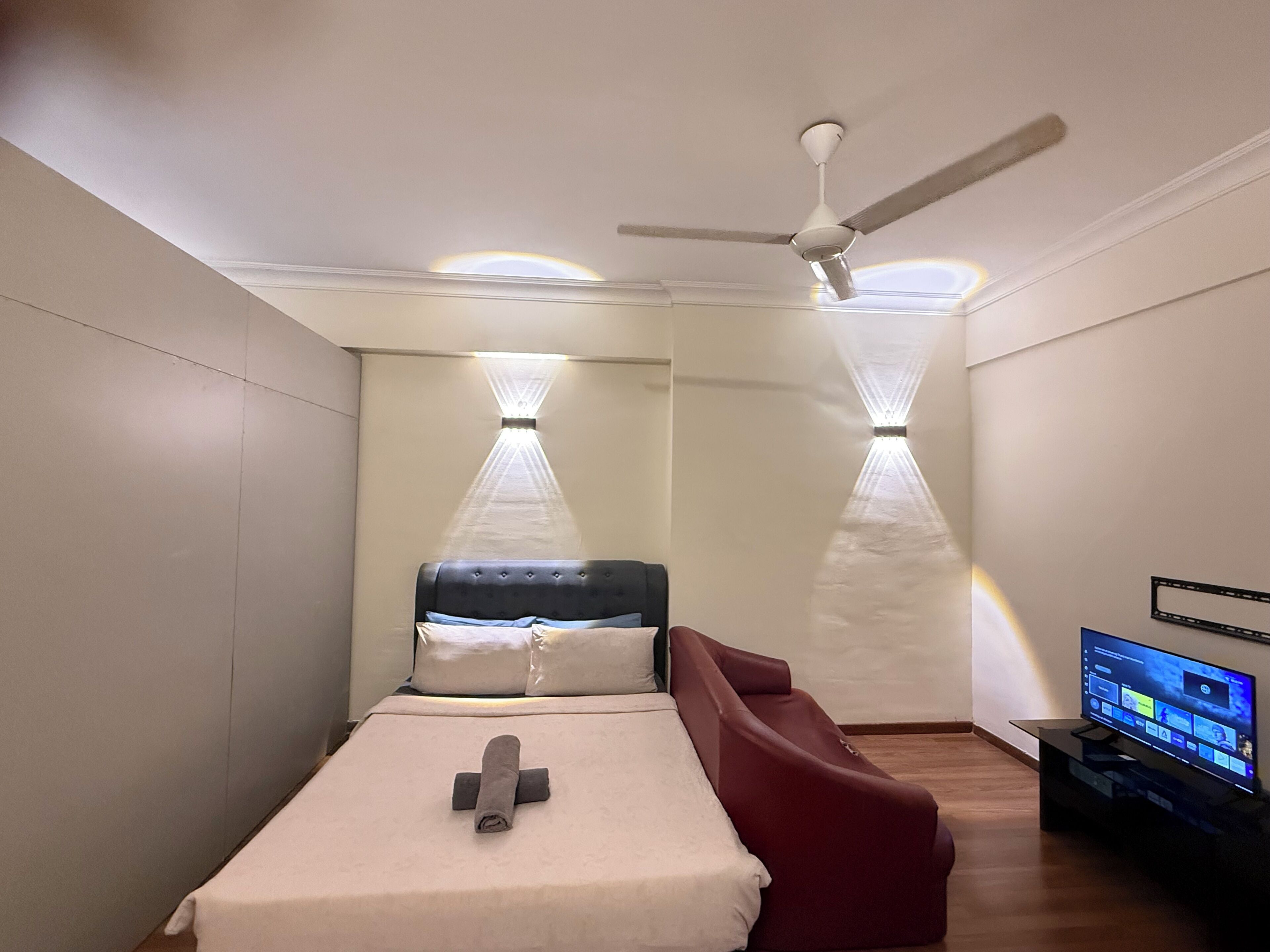 Een slaapkamer met een bed, een plafondventilator, inbouwverlichting en een televisie.