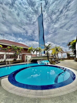 A swimming pool with a modern building in the background. - Casa Mutiara Apartments by Moonlight (Kuala Lumpur)
