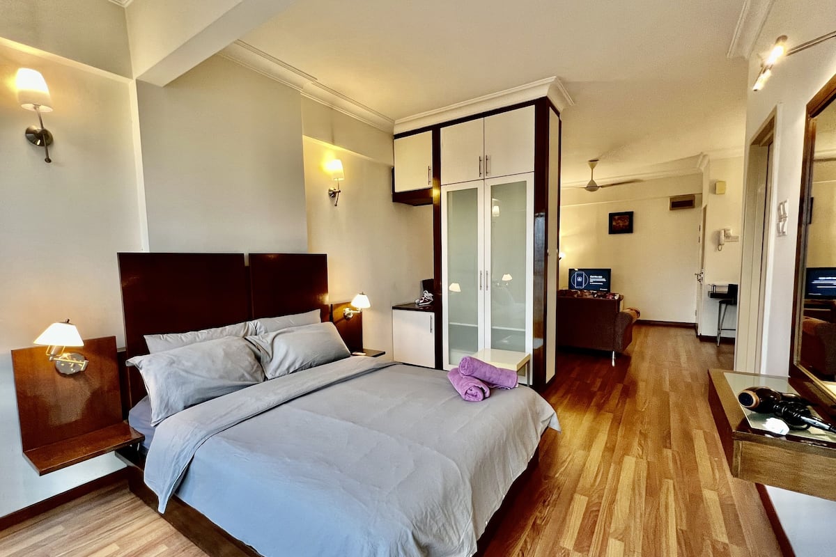 Una habitació d'hotel amb un llit, un armari, una taula de treball i una televisió.