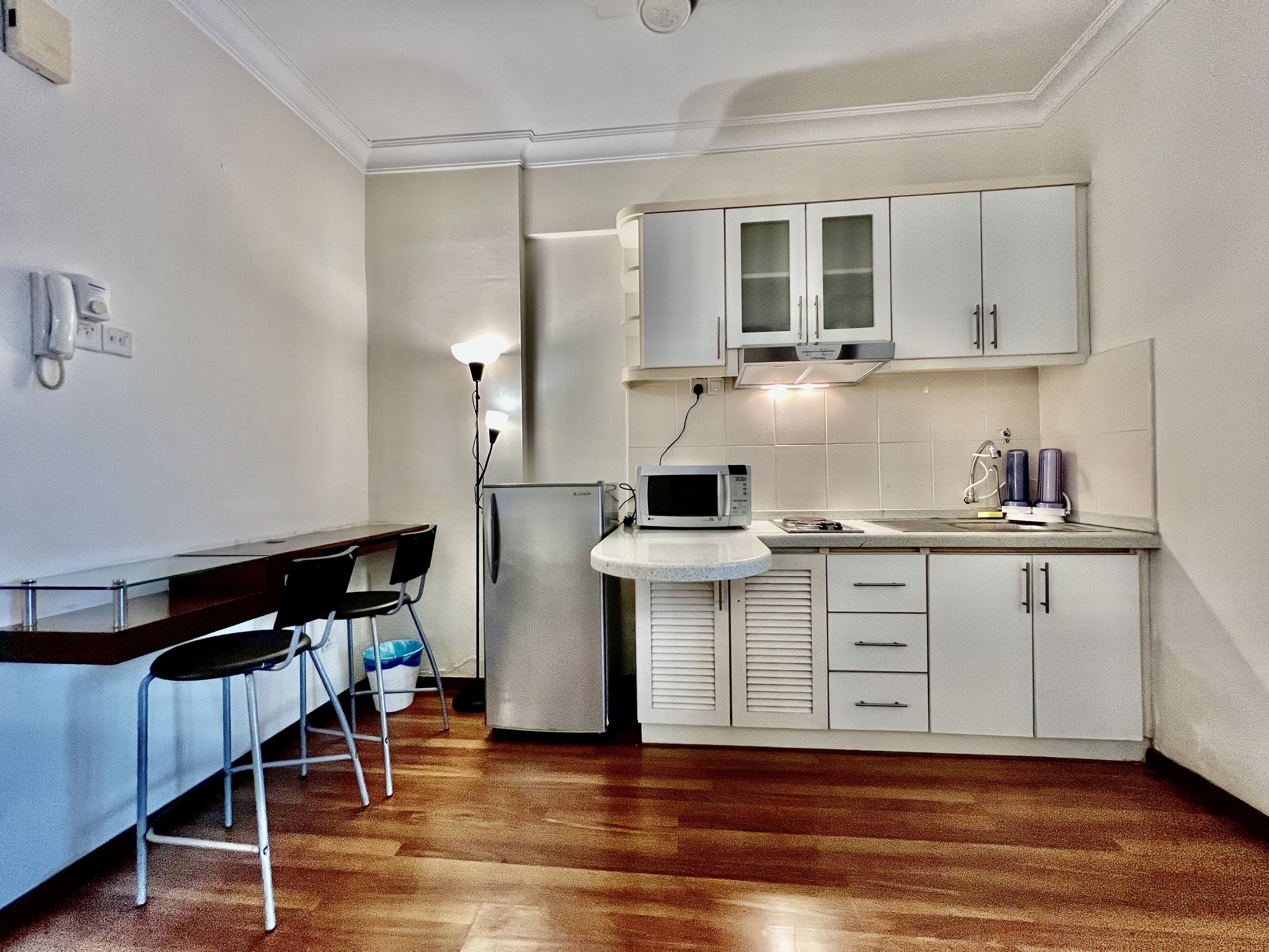A compact kitchen with a refrigerator, microwave, and cabinets. There is a small dining area with a table and chairs.