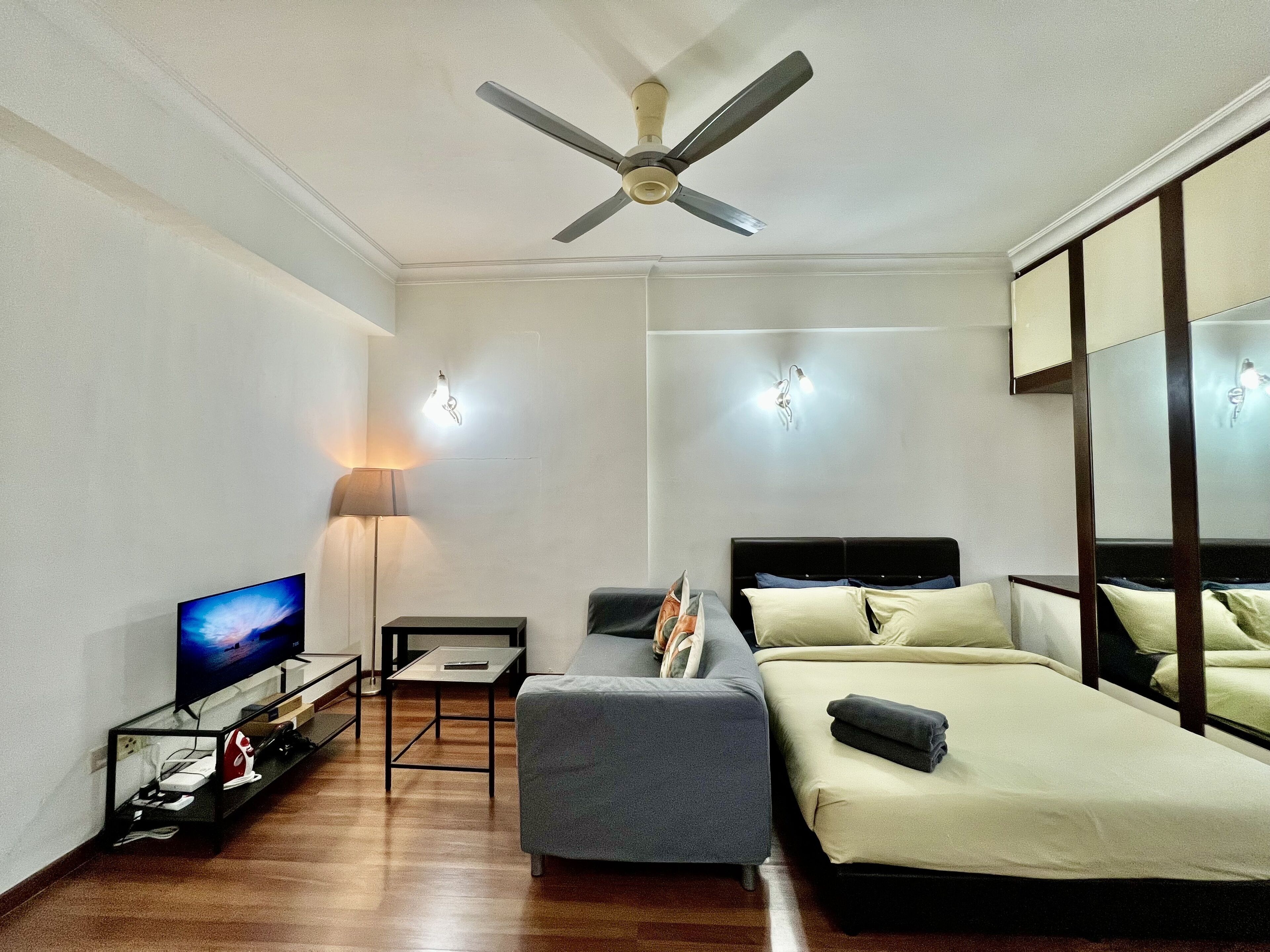 Ein Hotelzimmer mit Bett, Schreibtisch, Stuhl, Fernseher und Deckenventilator.
