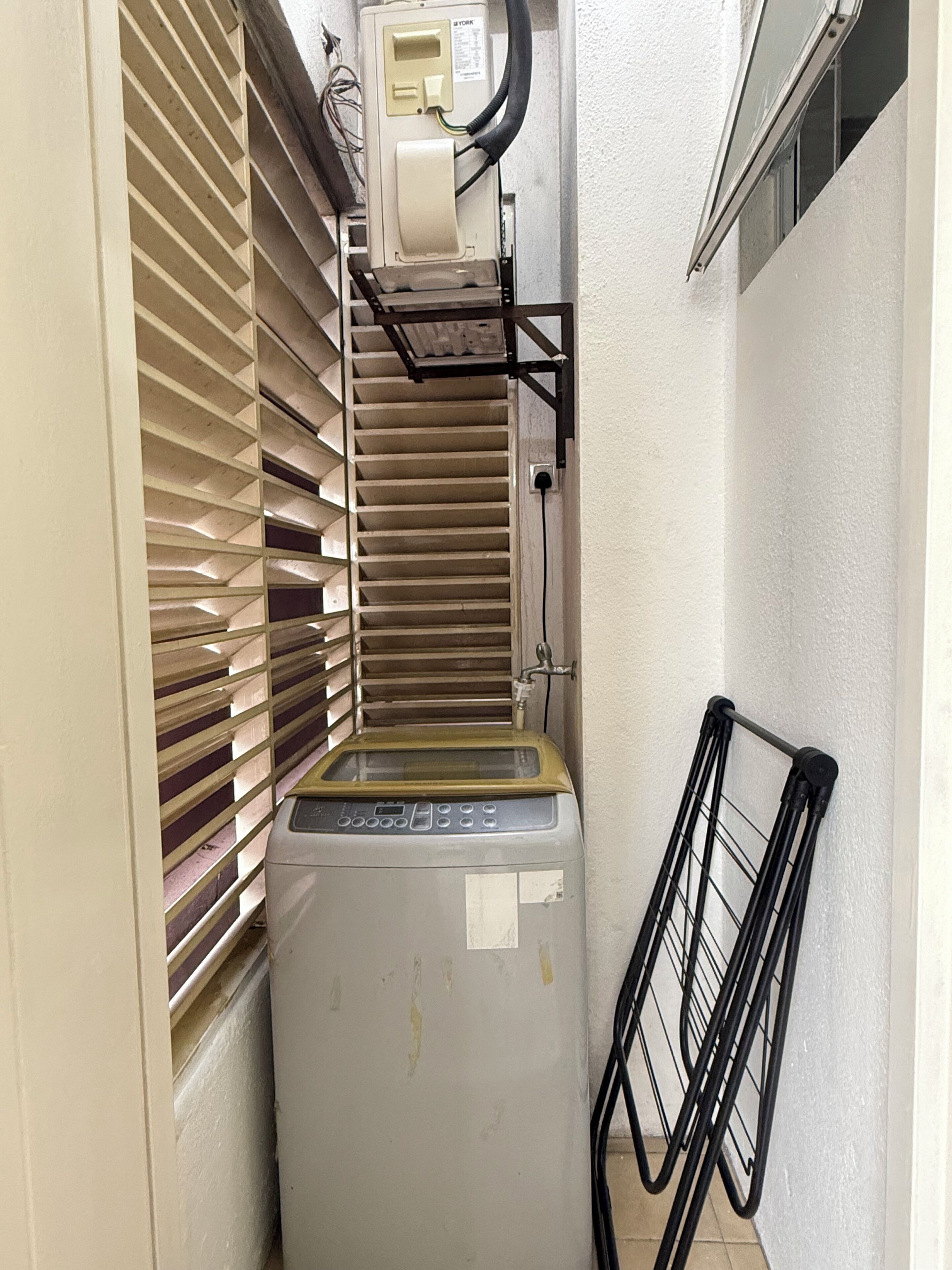 A compact utility room with a washing machine, a water heater, and a ventilation system.