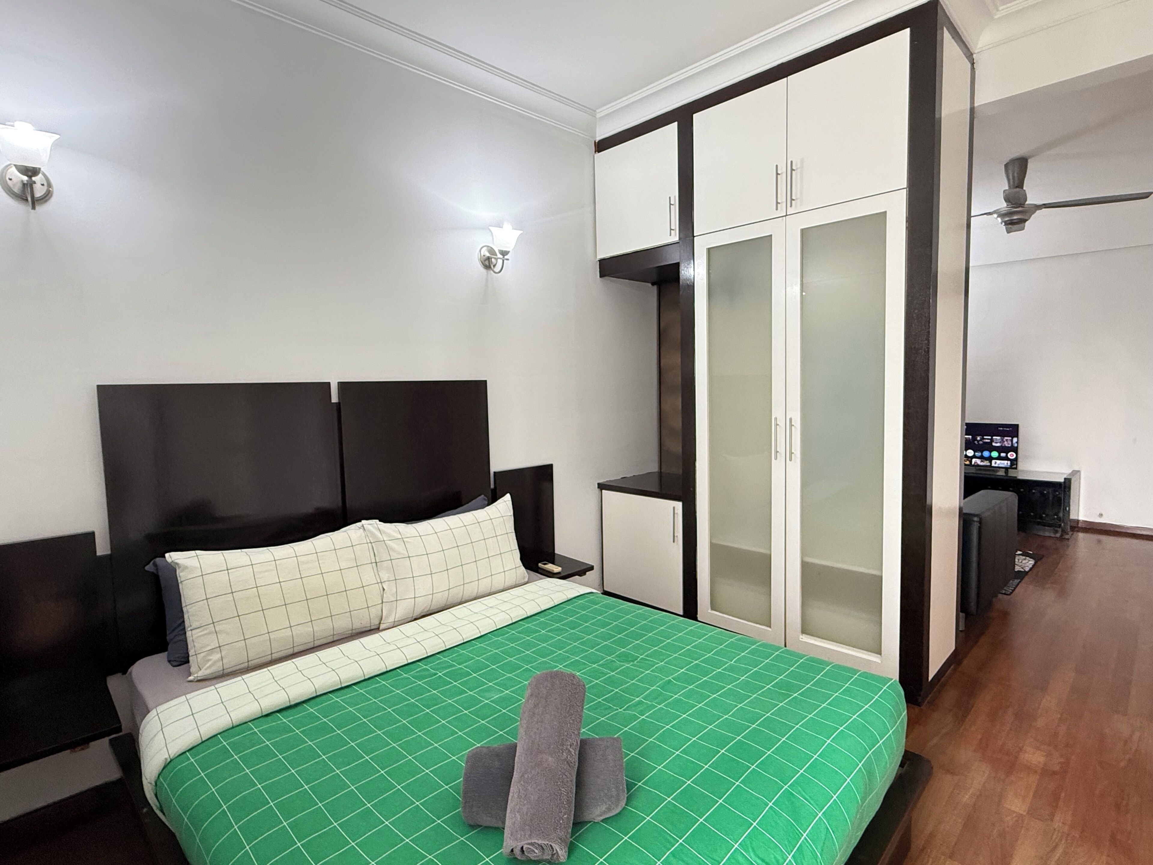 Un dormitorio con cama, armario, mesita de noche y televisor.