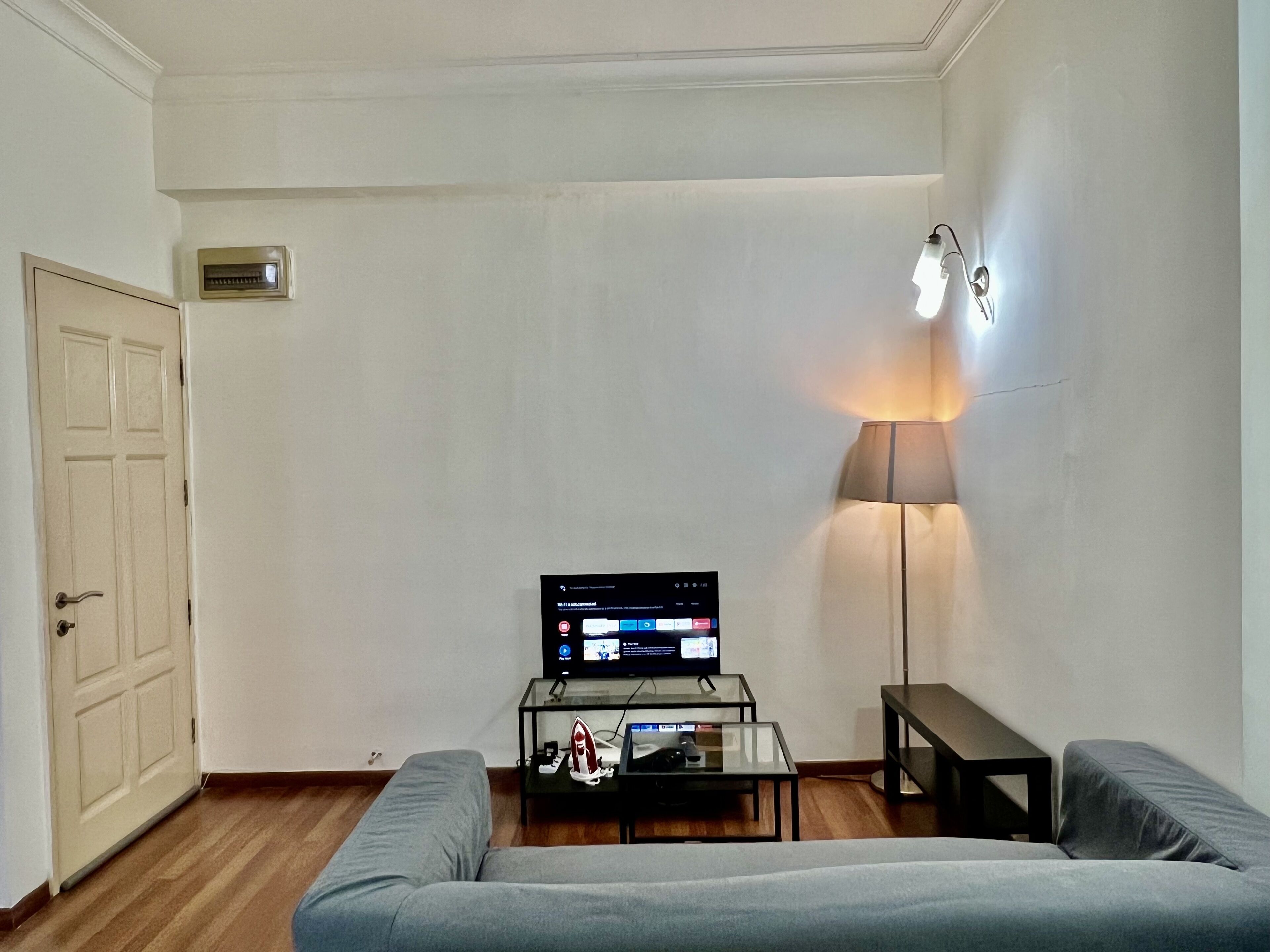 Una sala de estar con un sofá, una mesa de centro con un televisor, una lámpara y una puerta.