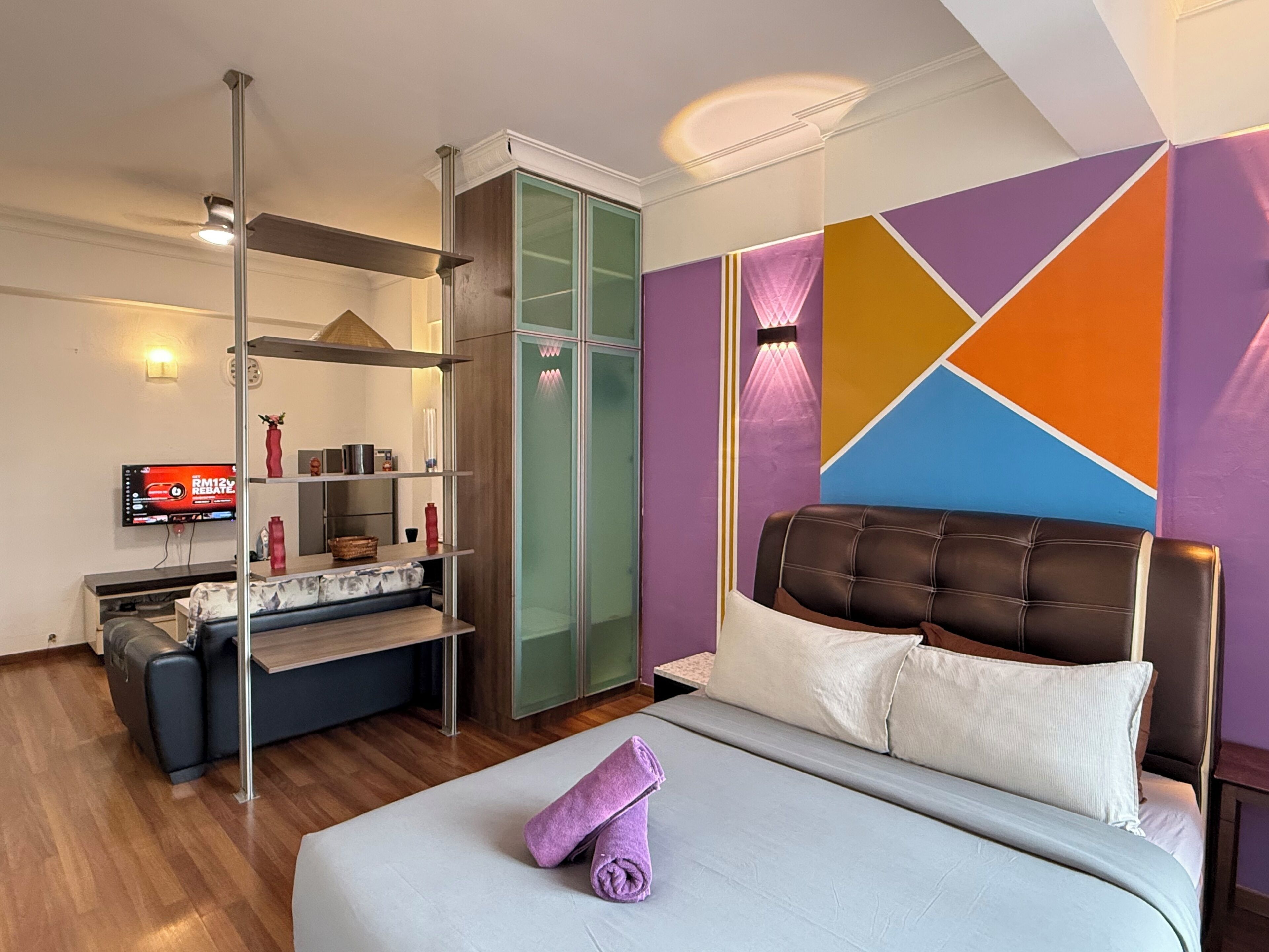 A modern hotel room with a bed, a sofa, a TV, and a wardrobe.