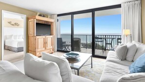 A hotel room with a balcony, a television, a sofa, and a dining table. - One Seagrove Place 0405 (Santa Rosa Beach)