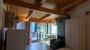 Un plafond en bois, un mur en pierre, un coin repas avec une table et des chaises, et une porte.