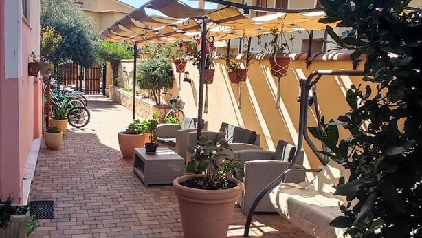 Une cour dallée agrémentée de plantes en pot, de sièges extérieurs et d’un espace abrité avec des parasols.