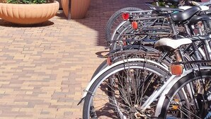 Une cour pavée où sont garés des vélos le long des murs, entourée de bâtiments dotés de terrasses et de plantes en pot.