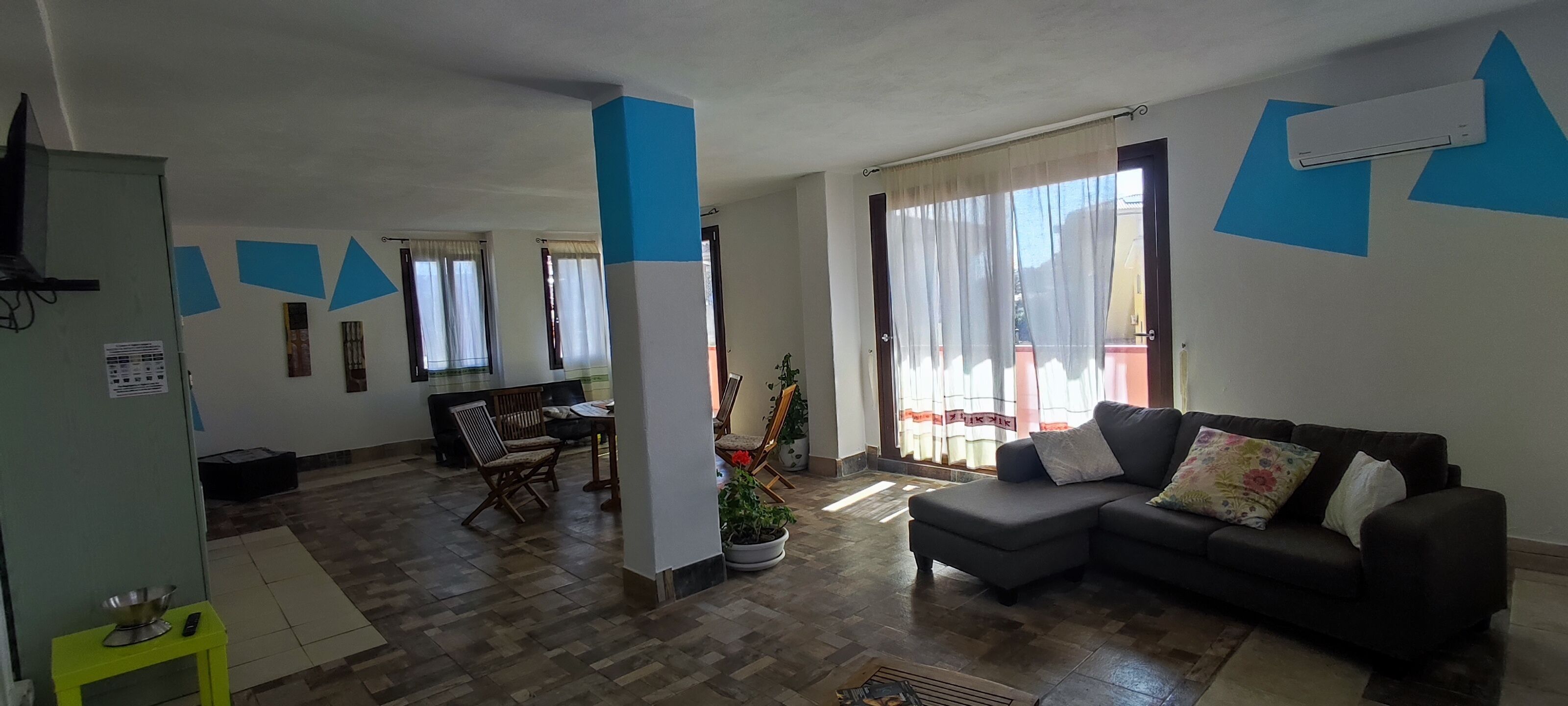 A living room with a sofa, a dining table with chairs, and a kitchen area.