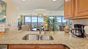 A kitchen with a double sink, wooden cabinets, and a coffee maker.