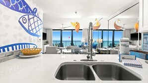 Una cocina moderna con un amplio ventanal con vistas al mar, una zona de comedor panorámica y una pared decorativa con motivos de peces.