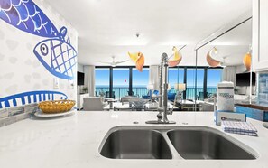 Cozinha moderna com uma grande janela para o mar, área de jantar com vista e parede decorativa com design de peixe.