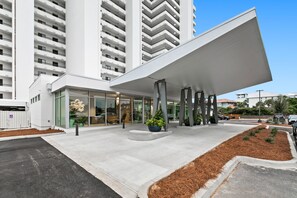 Stunning entrance with a large overhang and glass doors, surrounded by lush greenery.