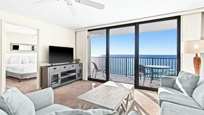 A hotel room with a balcony, a TV, a bed, and a seating area with a view of the ocean. - Family Beachfront Corner Unit Sleeps 6 (Santa Rosa Beach)