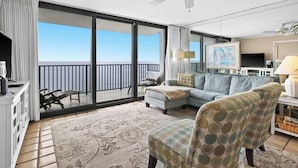 A spacious balcony with a view of the sea, a ceiling fan, a sofa, and a TV.