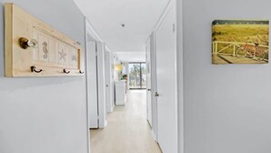 Ein Korridor mit weißen Wänden, einer Holztür mit Seepferdchen- und Sternenmuster-Dekoration sowie einem gerahmten Bild eines Fahrrads an der Wand.