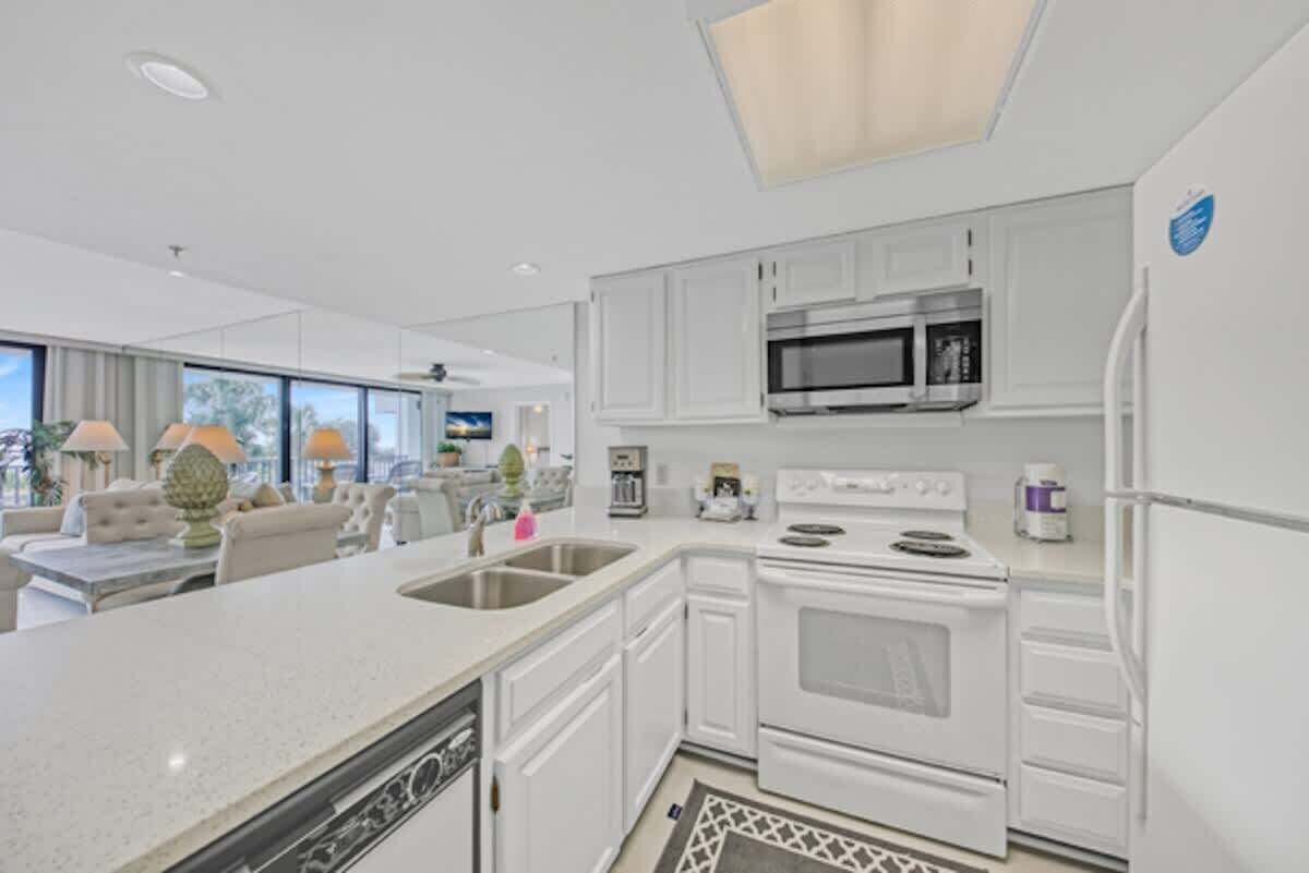 A modern kitchen with white cabinetry, stainless steel appliances, and a large window providing natural light.