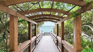 A wooden boardwalk leading to a gazebo with a view of the sea.