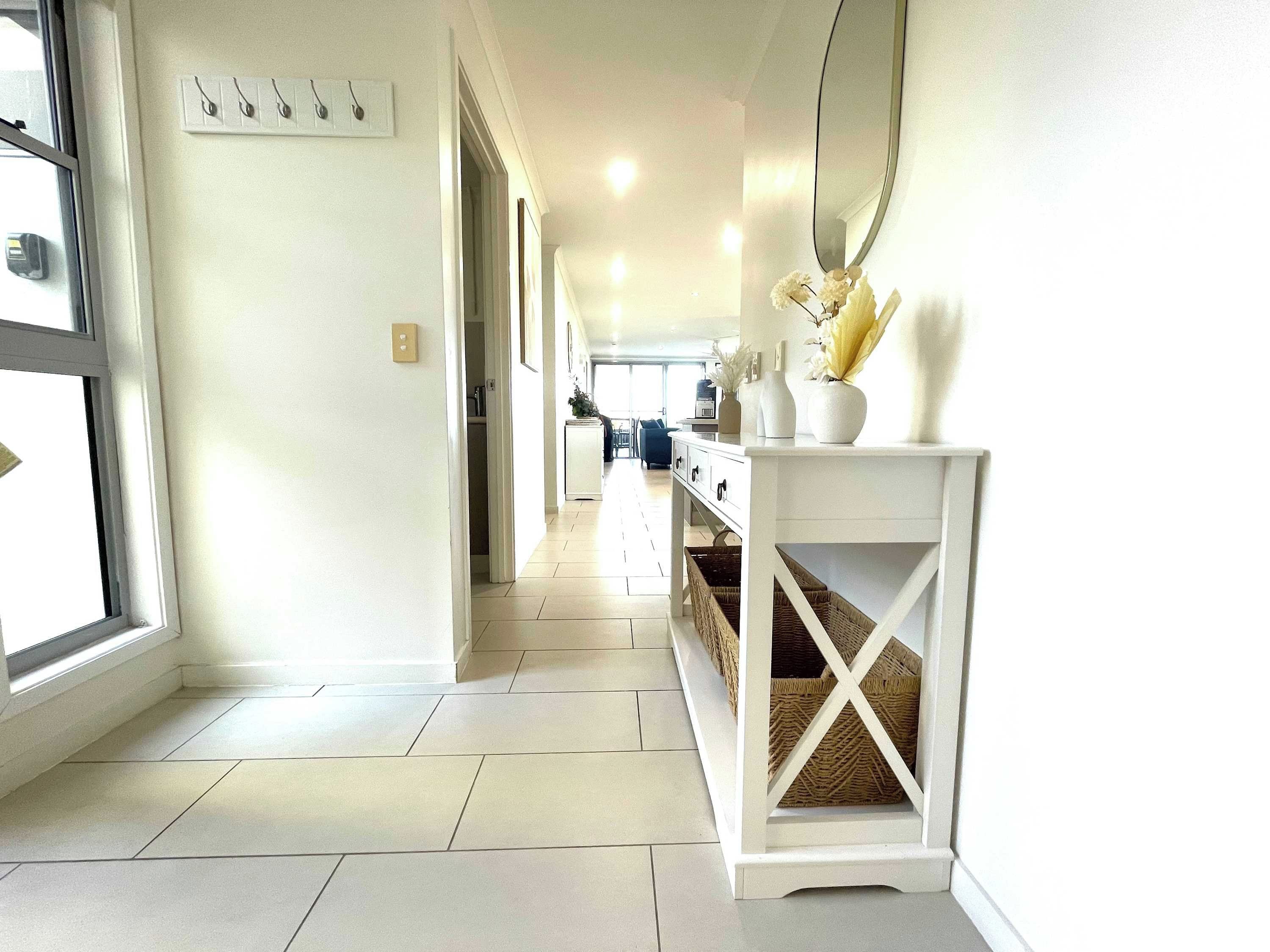 A hallway with a white console table, wicker baskets, and a large mirror.