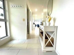 A hallway with a white console table, wicker baskets, and a large mirror.