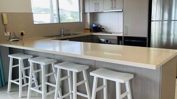 A modern kitchen with a large island, bar stools, stainless steel appliances, and a window providing natural light.