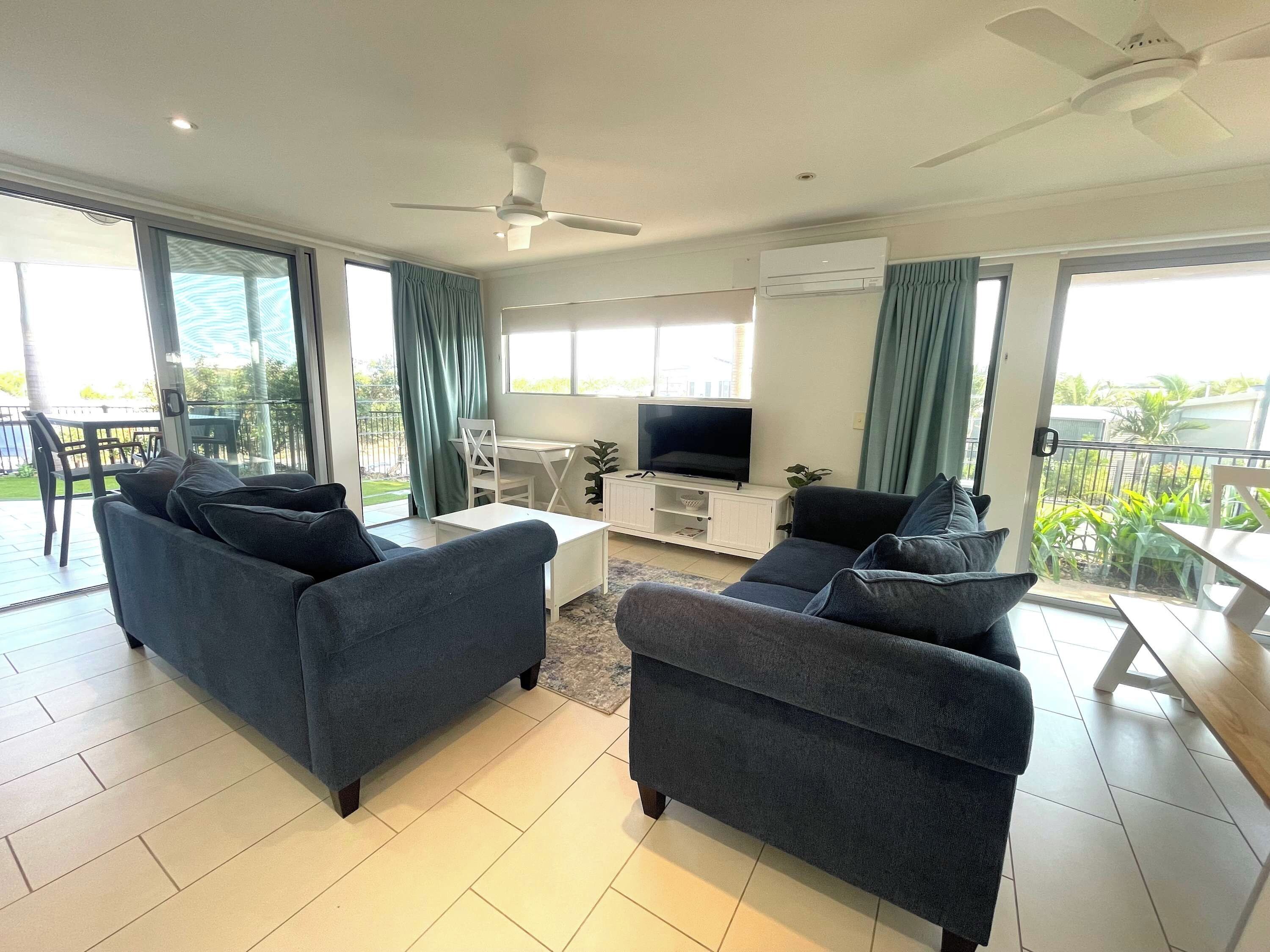 A modern living room with two sofas, a TV, and a balcony.