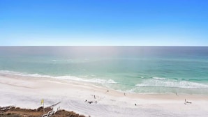 A beach with clear skies, calm waters, and a few people.