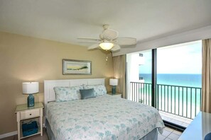 A bedroom with a bed, nightstands, a ceiling fan, a window with a view of the ocean, and a balcony. - One Seagrove Place 1205 (Santa Rosa Beach)