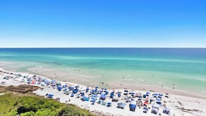 Een strand met veel parasols en mensen.