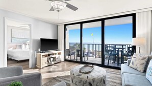 A modern hotel room with a balcony, a flat-screen TV, a sofa, and a coffee table. - One Seagrove Place 0202 (Santa Rosa Beach)