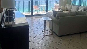 Un balcon spacieux avec vue sur la mer, un canapé blanc, une petite table et une lampe.