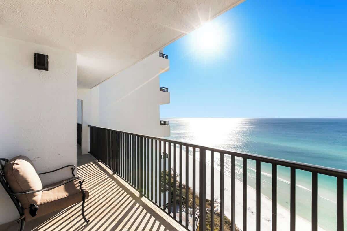 A balcony with a view of the ocean, a chair, and a railing.