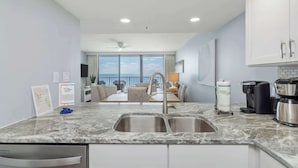 A modern kitchen with a large window, a sink, and a coffee maker. - One Seagrove Place 0807 (Santa Rosa Beach)