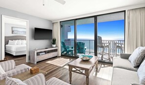A modern hotel room with a balcony, a flat-screen TV, a bed, a seating area with a table, and a view of the ocean. - One Seagrove Place 0807 (Santa Rosa Beach)