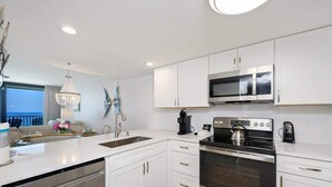 A modern kitchen with white cabinetry, stainless steel appliances, and a central island.